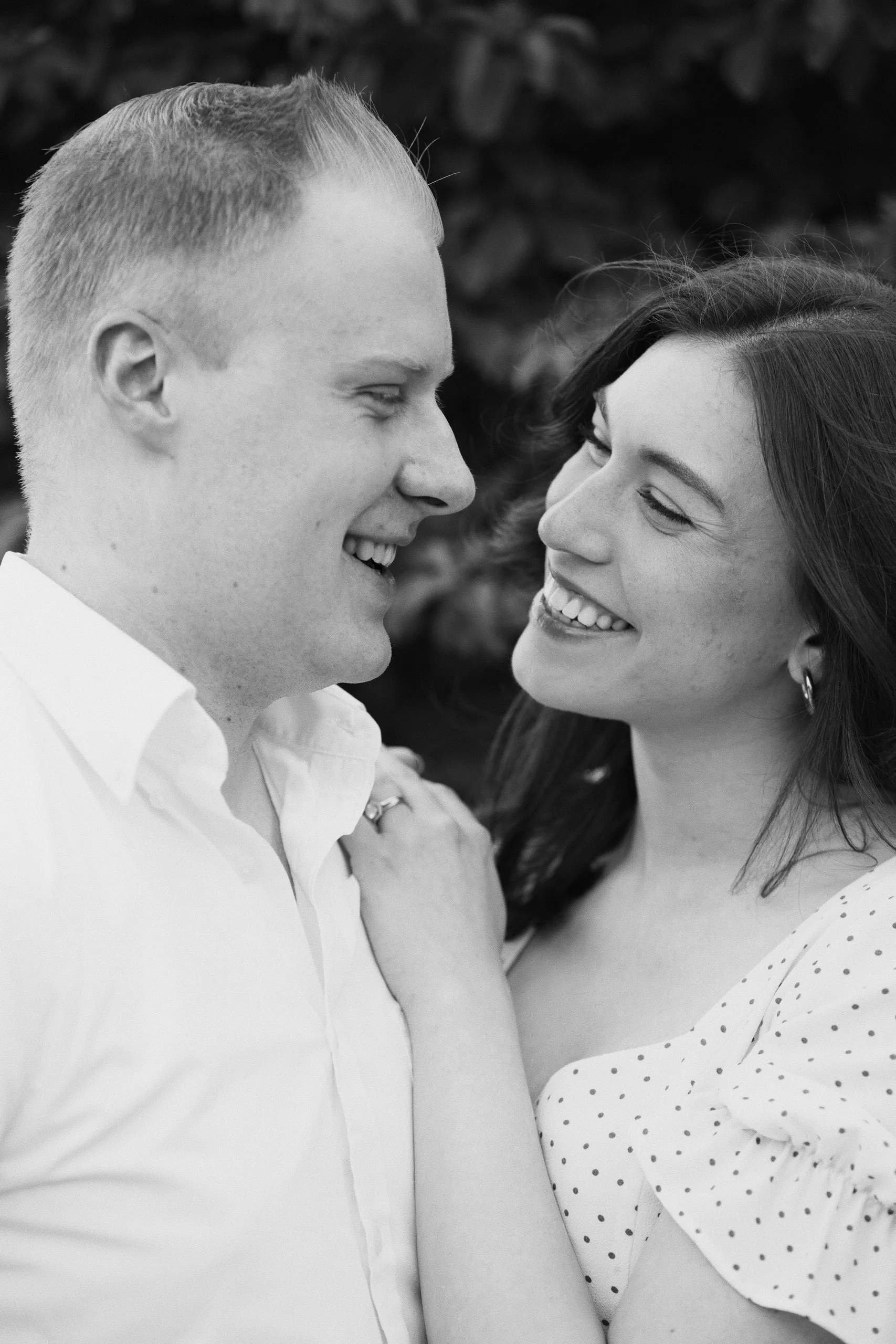 Black-and-white close-up of a couple smiling at each other, noses nearly touching.