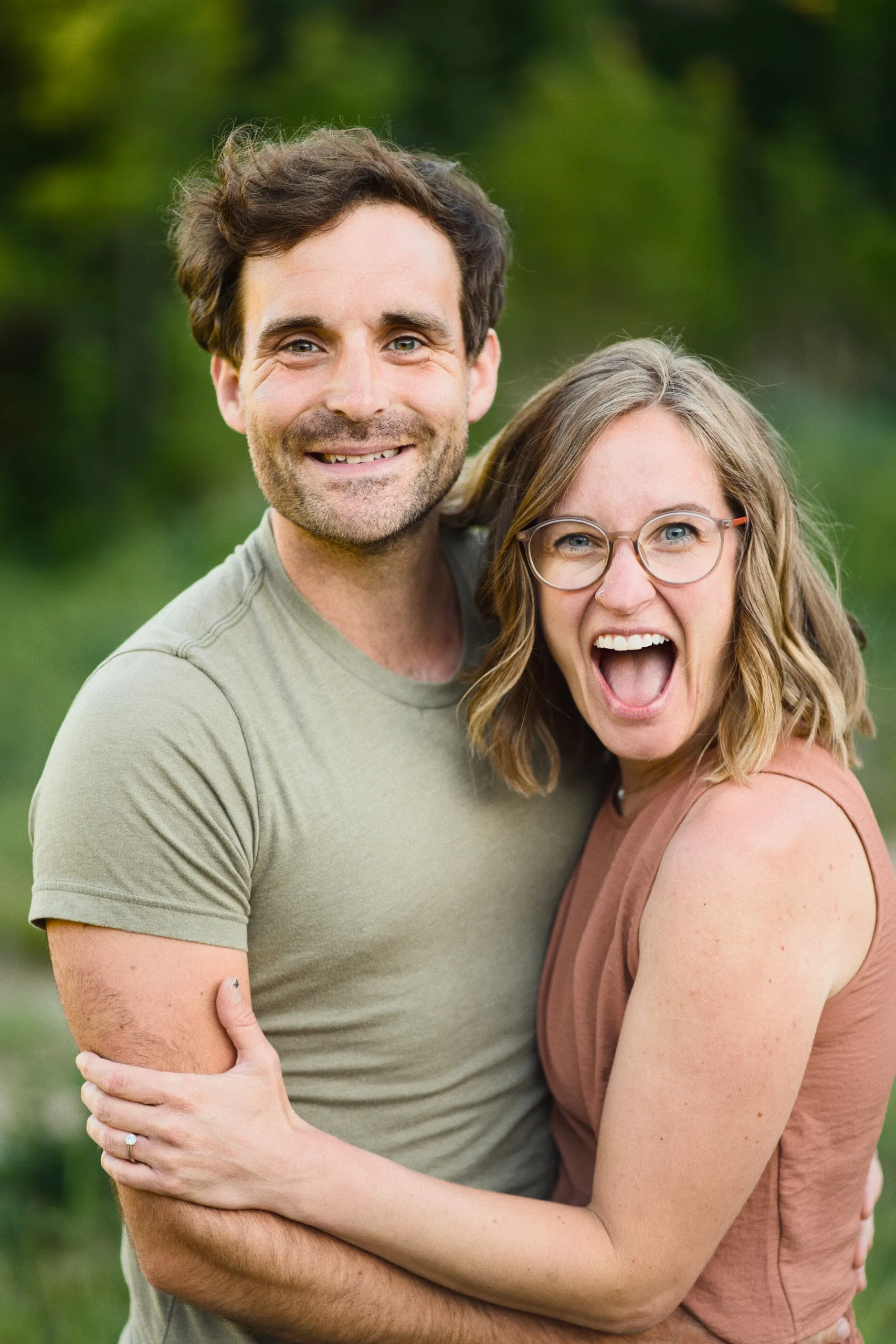 Close-up of a couple embracing, the woman laughing wide as the man smiles at the camera.